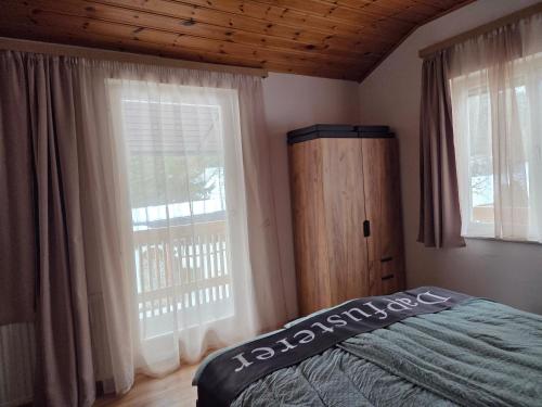 Un dormitorio con dos ventanas y una cama con colcha. en Ferienhaus DaPfusterer, en Bad Mitterndorf