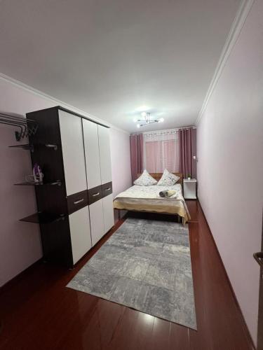 a bedroom with a bed and a cabinet and a rug at 3х комнатная квартира in Shymkent
