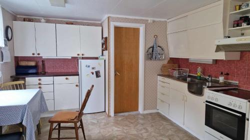 cocina con nevera blanca, mesa y silla en Mor's hus, en Vestvågøya