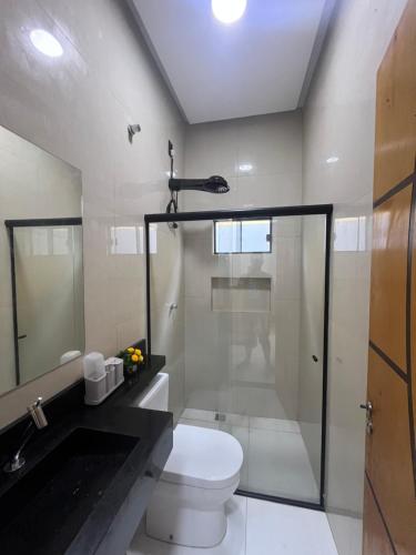 een badkamer met toilet en glazen douche bij Impera House Casa com piscina in Imperatriz