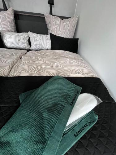 a bed with a green blanket and pillows on it at Weserbergland Lodge im Wiesenweg in Holzminden in Holzminden