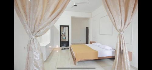 1 dormitorio blanco con cama y cortinas en AZURE stay happy, en Pudunagaram