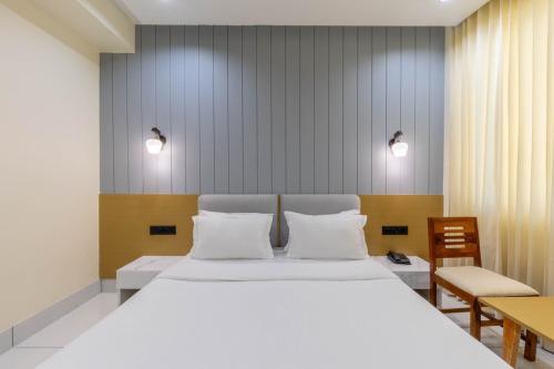 Un dormitorio con una gran cama blanca con dos almohadas. en hotel monville akota, en Vadodara