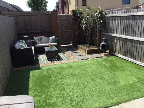 a backyard with green grass and a fence at Coastal Comfort - Two Bed Terrace on Barry Island in Barry