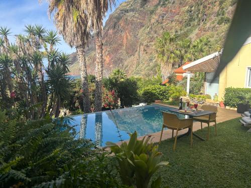 a pool with a table and chairs next to a house at Suite Bela Vigia 4 in Jardim do Mar