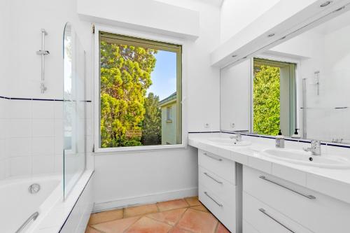 a white bathroom with two sinks and a window at Villa Séquoia Saint-Germain-en-Laye in Saint-Germain-en-Laye