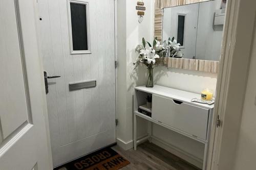 a bathroom with a door and a sink and a mirror at Coastal Comfort - Two Bed Terrace on Barry Island in Barry