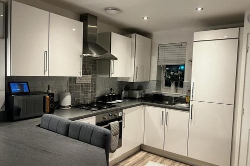 a kitchen with white cabinets and a stove at Coastal Comfort - Two Bed Terrace on Barry Island in Barry