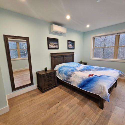 Powder Run - Modern 3BR Basecamp with Hot Tub, AC, EV Charger & Flat Parking في North Sherburne: غرفة نوم بسرير وخزانة ومرآة