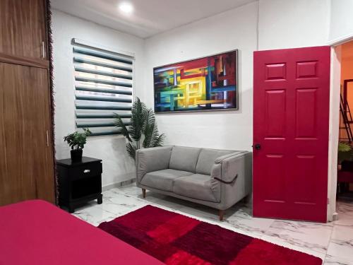 een kamer met een bank en een rode deur bij La Puerta Blanca #5 in Puerto Vallarta