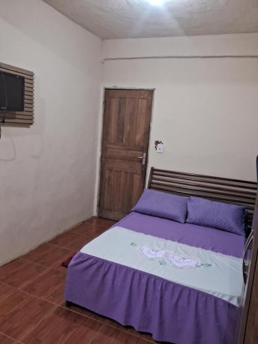 a bedroom with a purple bed and a tv at Recanto feliz in São Thomé das Letras