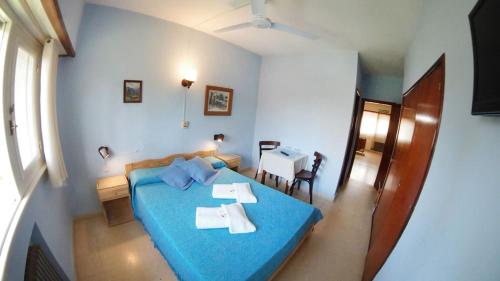 a bedroom with a blue bed and a table at Hostería Bavaria por Las Grullas in Villa Gesell