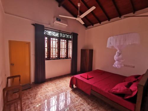 a bedroom with a red bed and a large window at Green Relax Villa in Mirissa