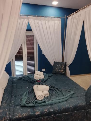 a blue bedroom with a large bed with white curtains at Regia Dimora in Eboli