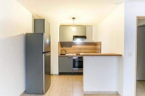 eine Küche mit Kühlschrank und Spüle in der Unterkunft Appartement avec balcon parking Alès centre in Alès