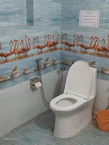 a bathroom with a toilet with flamingos on the wall at COMMANDER VILLa in Mukteswar