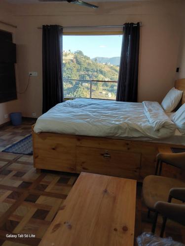 a bedroom with a bed and a large window at COMMANDER VILLa in Mukteswar