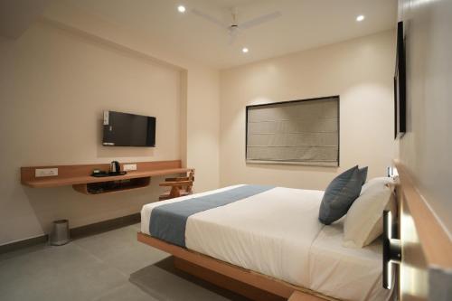 ein Schlafzimmer mit Bett, Schreibtisch und Fernseher in der Unterkunft Kolas Grand - Hotel and Convention Center in Warangal