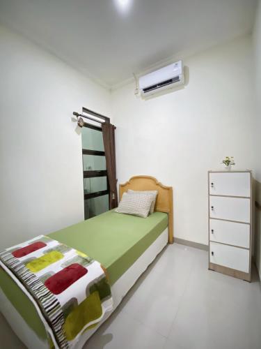a small bedroom with a bed and a dresser at Homestay Griya Manggisan in Banyurojo