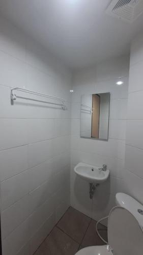 a white bathroom with a sink and a mirror at Alton City Loft in Jatingaleh