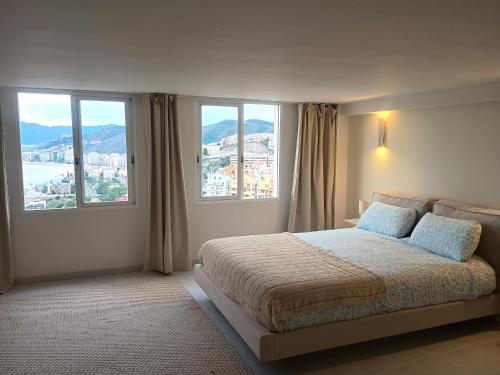 Un dormitorio con una cama grande con grandes ventanales. en LOFT ROYAL - apartamento "loft" con terraza y vistas al mar, en Faro de Cullera