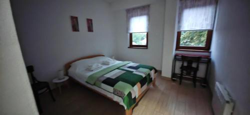 a small bedroom with a bed and two windows at Apartman Besu in Vrnjačka Banja