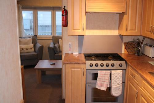 a kitchen with a stove and a living room at Annandale skegness in Skegness