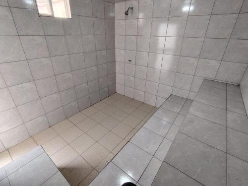a white tiled shower with a hole in the floor at Coney Camping in Ambato