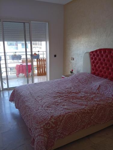 Un dormitorio con una cama grande con una colcha roja. en Appartement familial à 100 m de la mer, en El Harhoura