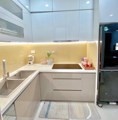a kitchen with white cabinets and a sink and a refrigerator at Hiền Apartment in Thôn Văn Dương