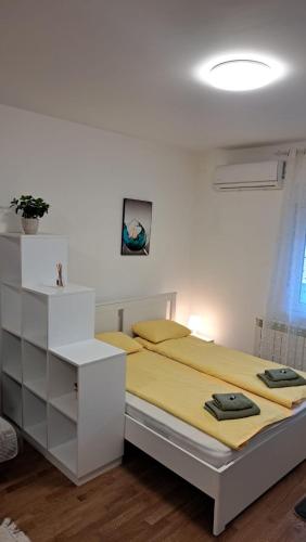 a white bedroom with a bed with a yellow blanket at Apartment Sanja in Belgrade