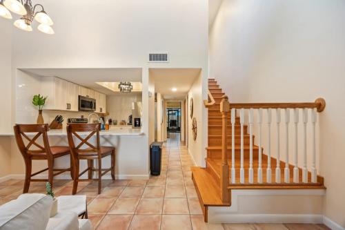 a kitchen and living room with a staircase and a table at Beach Townhome Steps from Downtown Cocoa Beach in Cocoa Beach