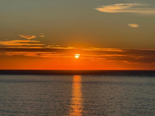 a sunset over the ocean with the sun setting at MADA HOUSE's in Sesimbra