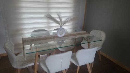a glass table with white chairs and a telephone at Casa mirador de volcanes, 6 personas in Llanquihue