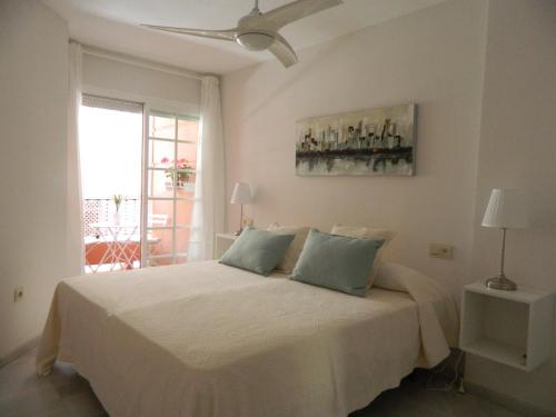 1 dormitorio con 1 cama blanca y ventilador de techo en Apartamento Miramar en Málaga