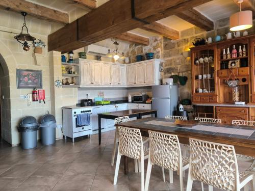 a kitchen with a table and chairs and a refrigerator at Il figolla farmhouse private pool & sea view in Xagħra