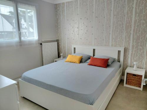 a bedroom with a white bed with two colorful pillows at Maison Dizavel in Le Croisic