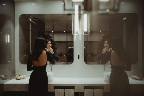 a woman brushing her teeth in front of a bathroom mirror at Alambique - Hotel Resort & Spa in Fundão