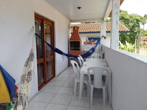 a patio with white chairs and a table on a balcony at Casa em Ubatuba beach two in Ubatuba