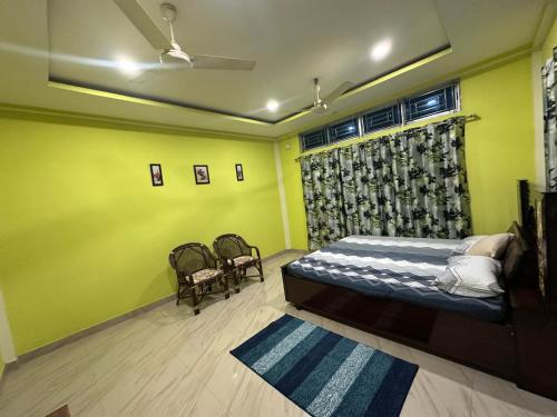 a bedroom with green walls and a bed and two chairs at KARDOM Homes Moran in Morānha