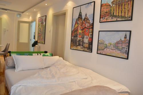 a bedroom with a white bed with pictures on the wall at Su inn apartman in Subotica