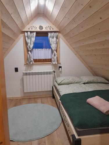 a small attic bedroom with a bed and a window at Domek GAWRA in Ząb