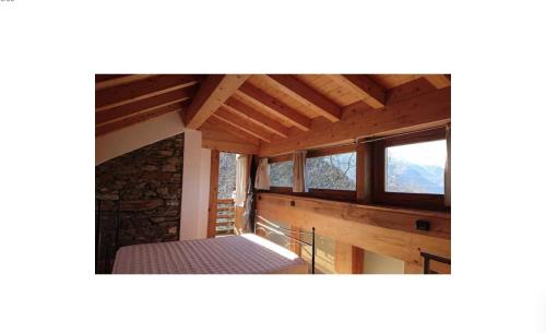 a bedroom in a log cabin with windows at Rustico Prato Grande con vista lago in Carriola