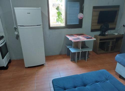 a living room with a refrigerator and a table at Kitnet geminada próximo da praia in Torres