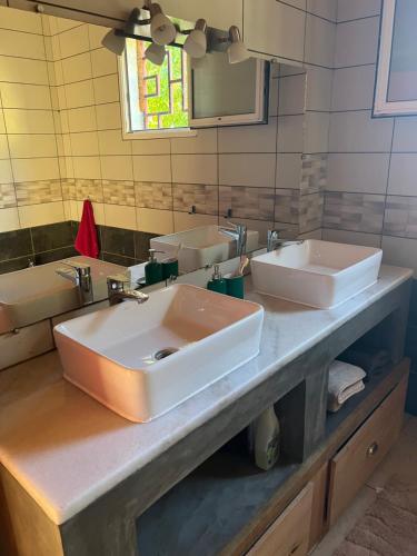 un bagno con due lavandini e uno specchio di Villa en face de pain de sucre 