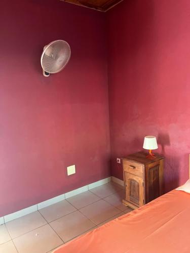 una camera da letto con una parete rossa, un letto e un ventilatore di Villa en face de pain de sucre 