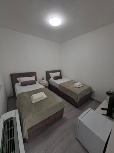 a room with two beds and a table with a tv at Pansion Kod Brajlovica in Tuzla