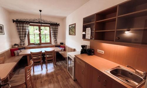 Una cocina con fregadero y una mesa con sillas. en Hotel Garni Pension zur Wacht, en Strobl