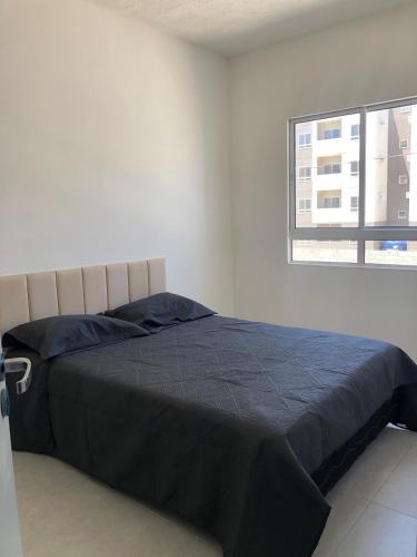 Una cama en una habitación blanca con ventana. en Apartamento completo com lazer, en João Pessoa