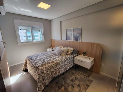 a small bedroom with a bed and a window at Praia e mar in Tramandaí